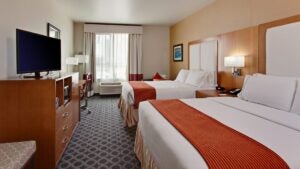 hotel room interior with two beds, tv, window, and lamps